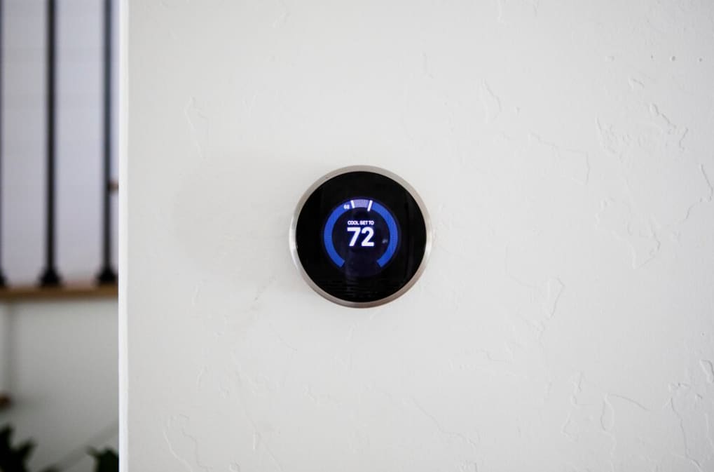 A modern Nest thermostat displaying a cool temperature of 72 degrees