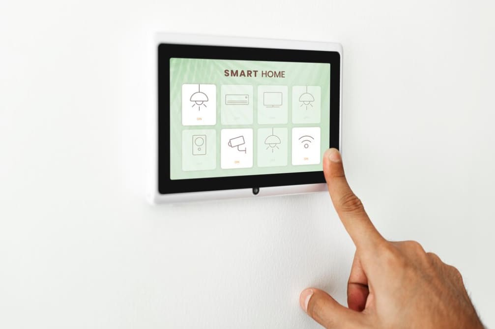 Hand pressing a smart home control panel mounted on a wall